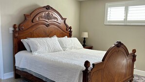 A wooden bed with a headboard, a bedside table with a lamp, and a patterned rug. - Waterfront Home on Canal - Heated Pool, Free use of Pontoon Boat! Discount's (New Port Richey)