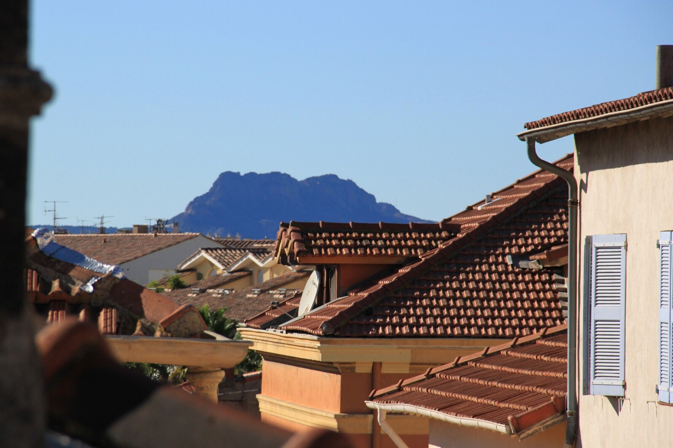 A view of terracotta-roofed buildings with a mountain in the background.