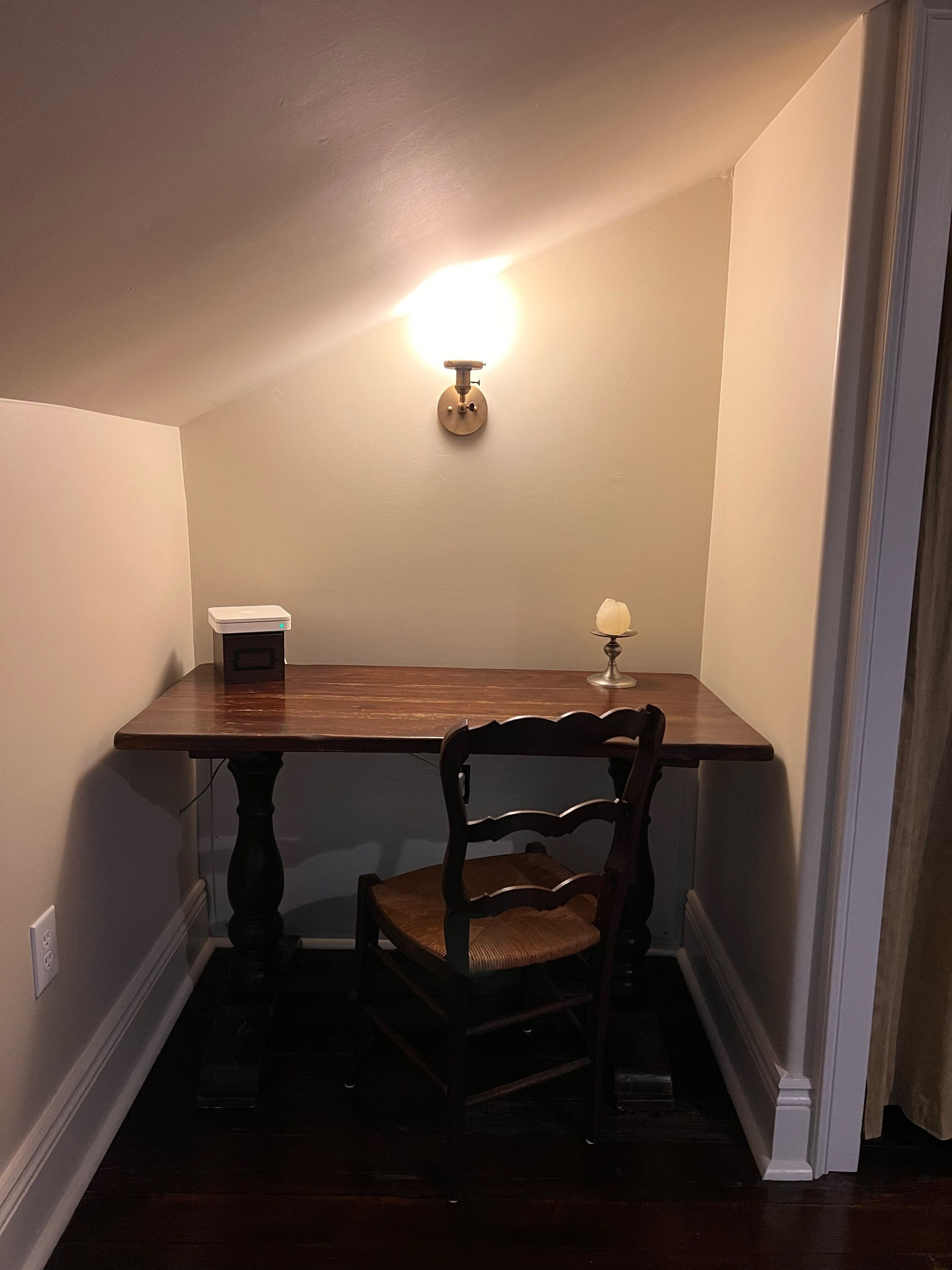 Un coin repas comprenant une table en bois, une chaise, un luminaire fixé au mur et une petite lampe de table.