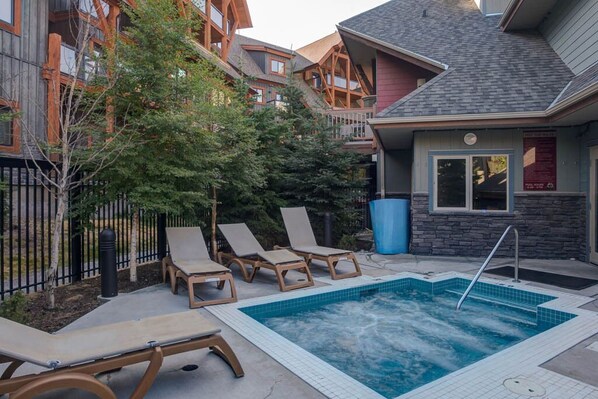Relax by the pool with a hot tub and lounge chairs.