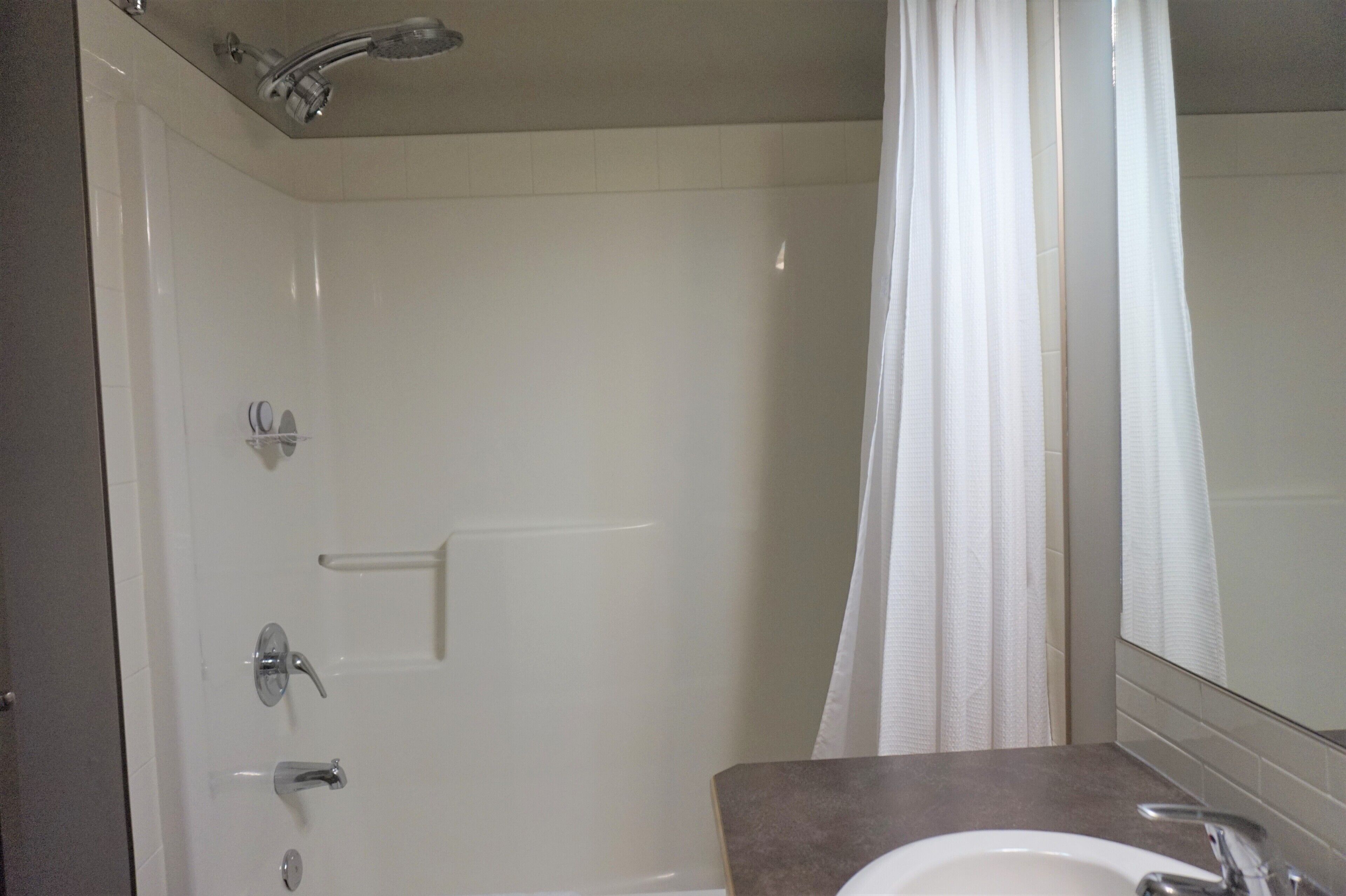 A bathroom with a shower, a sink, and a mirror.
