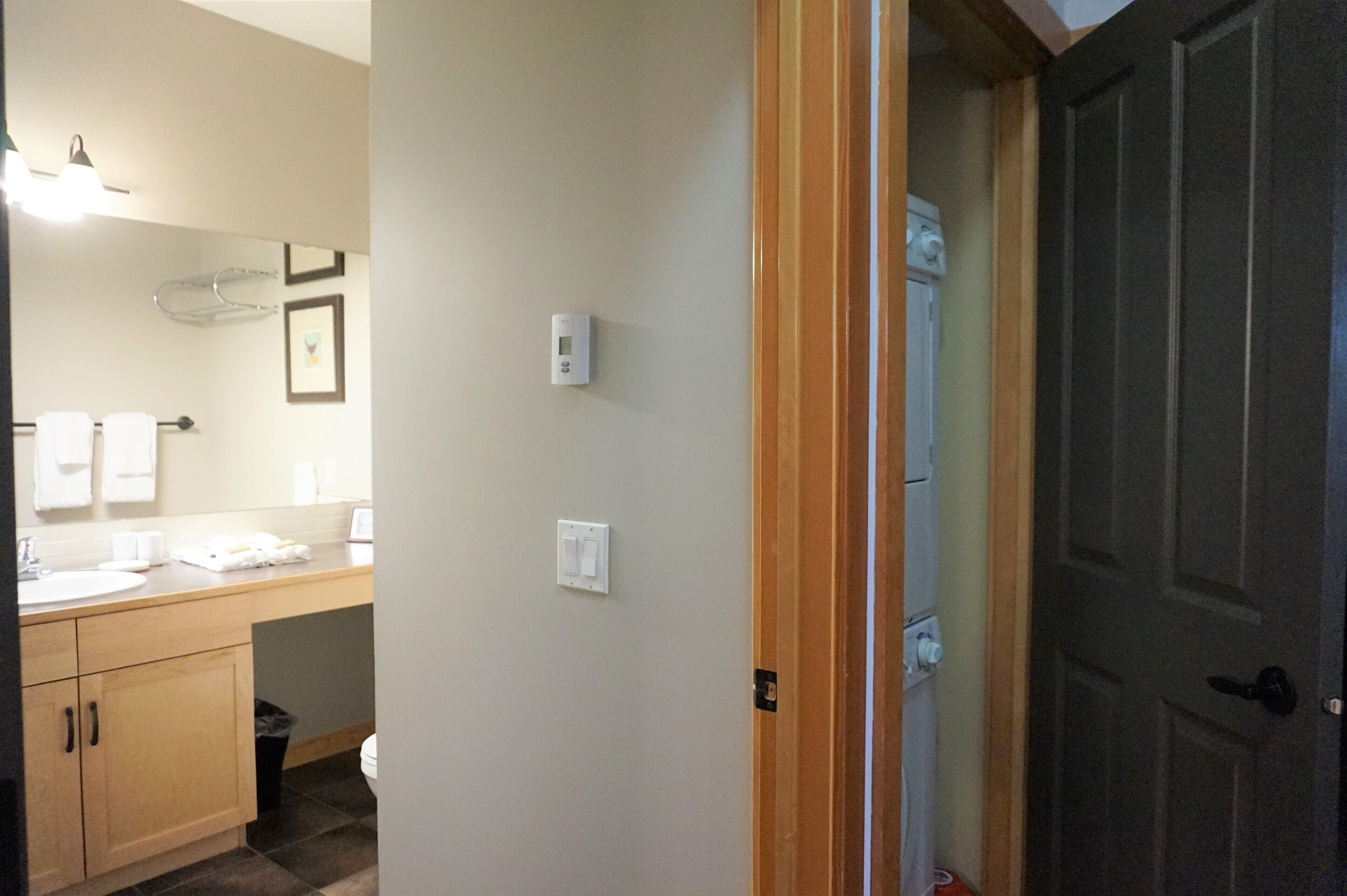 Une salle de bain équipée d’un lavabo, d’un miroir, d’un porte-serviettes et d’une porte donnant sur une autre pièce.