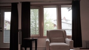 A room with a beige armchair, a small table, and a standing heater. - Premium 2 Bedroom, 2 Bath Condo w/central Air Conditioning- Lodges at Canmore (Canmore)
