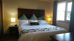 Relax in a spacious room with a large bed, featuring a comfortable headboard and plush pillows, and enjoy the soft glow of bedside lamps.