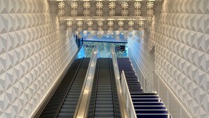 An escalator with geometric wall patterns and directional signs.