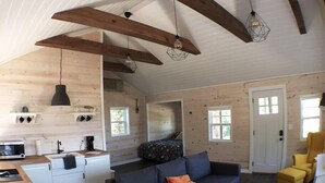 L’intérieur d’un chalet accueillant, avec une cuisine, un canapé et un fauteuil jaune.