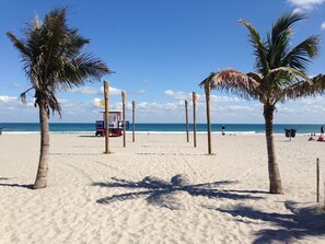 A beach with palm trees, a lifeguard tower, and the ocean in the background.