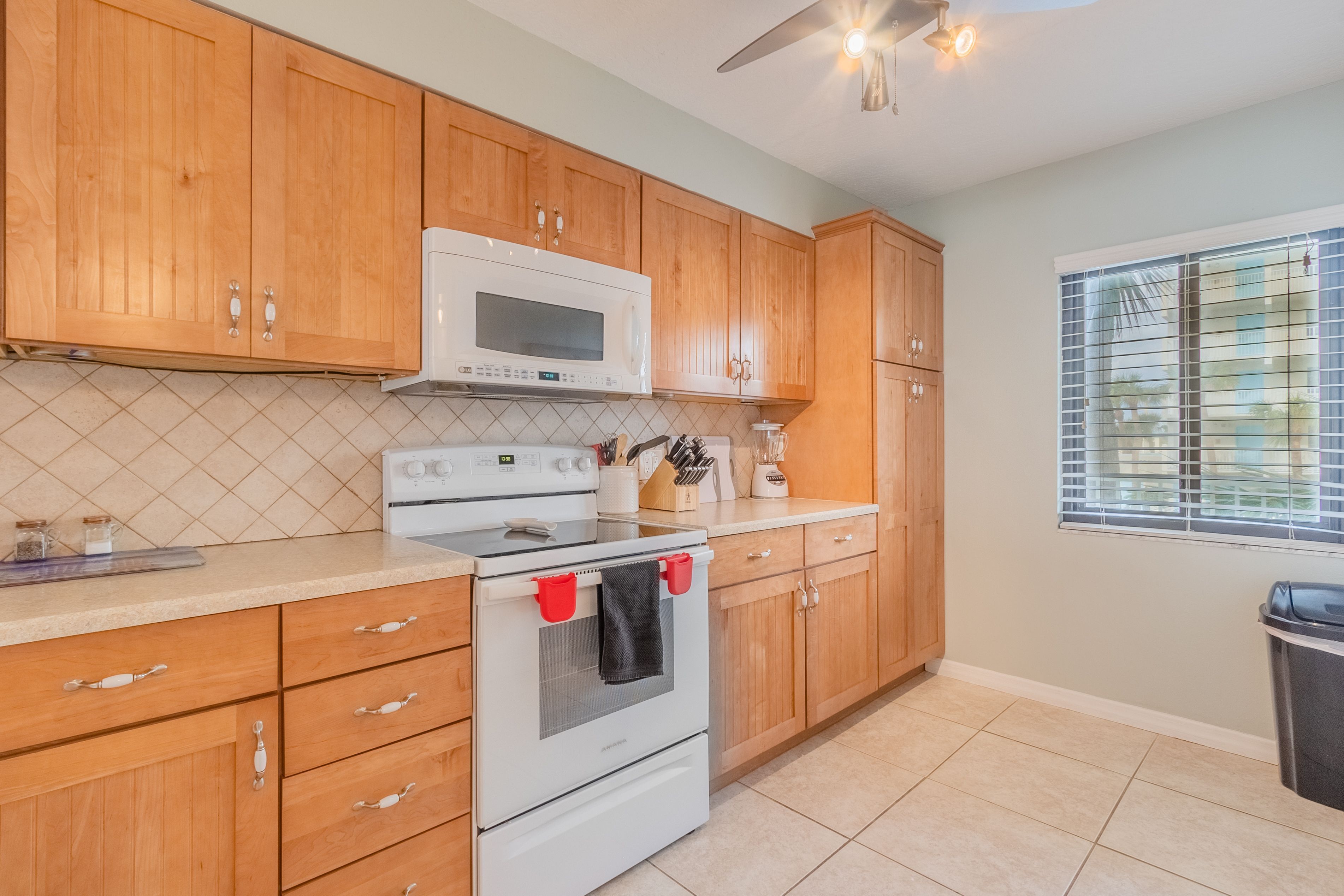 A kitchen with wooden cabinets, a white stove, and a microwave.