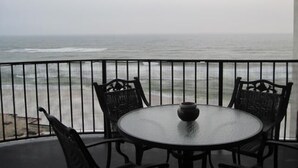 A balcony with a round table and four chairs, overlooking the ocean.