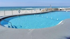 A pool with a clear view of the ocean and a railing.