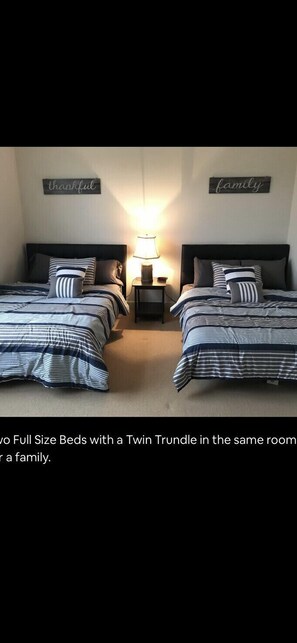 Two full-size beds with matching twin trundles, a nightstand, and wall-mounted signs.