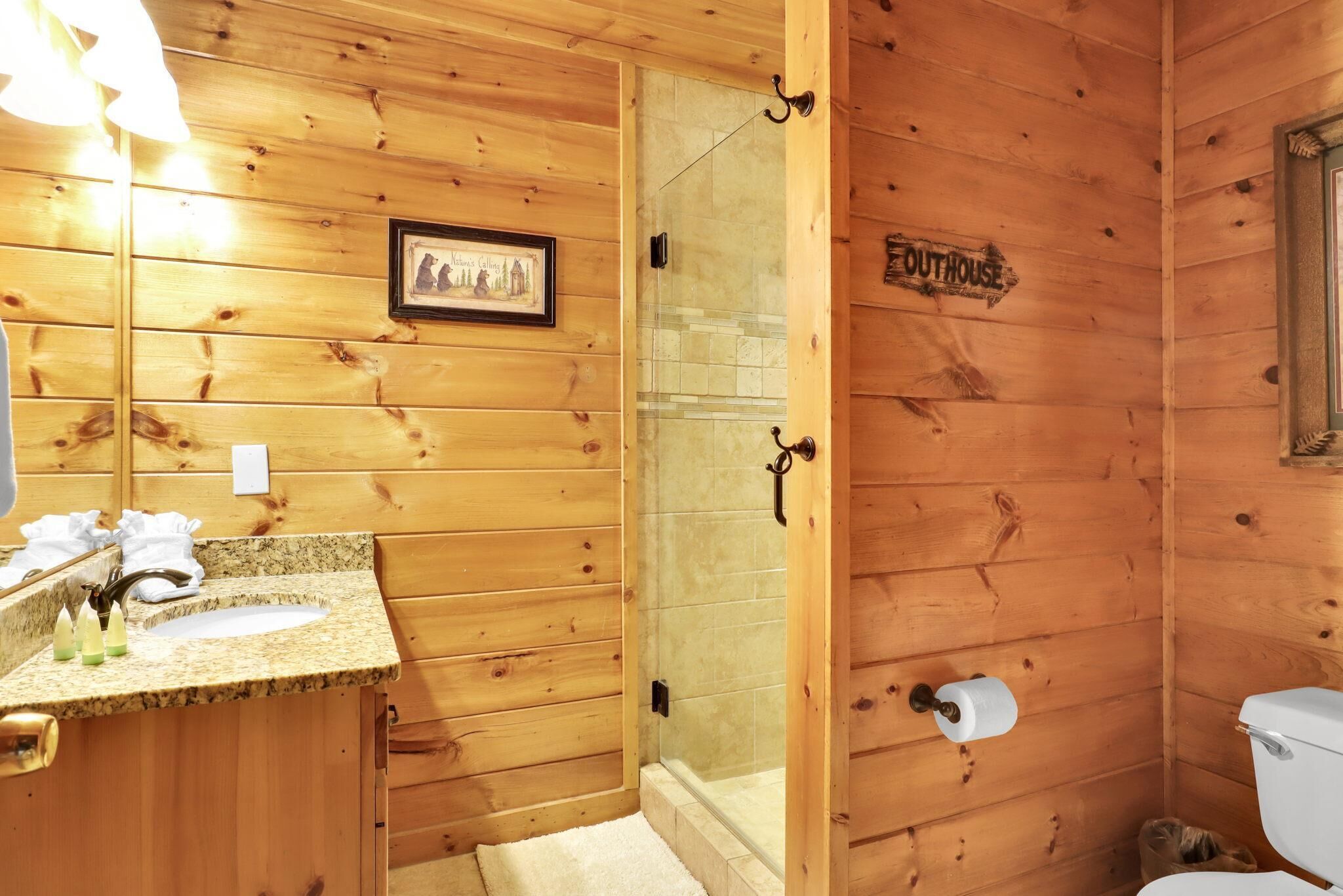 A wooden cabin bathroom with a sink, toilet, and shower.
