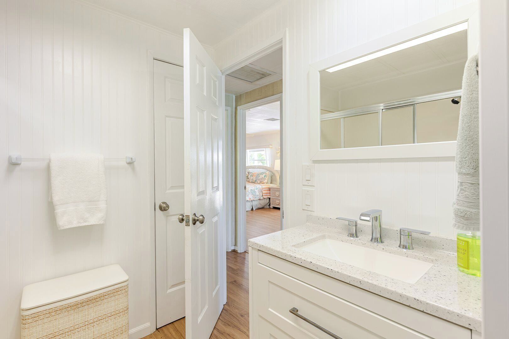 Une salle de bain avec un meuble-lavabo blanc, un miroir et un porte-serviettes.