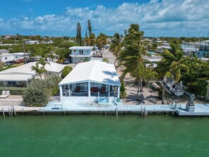 A coastal property with a pool, a covered outdoor seating area, and a view of the ocean.