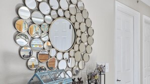 A wall decorated with a circular arrangement of mirrors, a vintage blue glass house, and a wooden dresser with drawers. - Next to Silver Dollar City, King Master, 2BR 2BA, Full Size Kitchen, 20ft Patio (Branson)