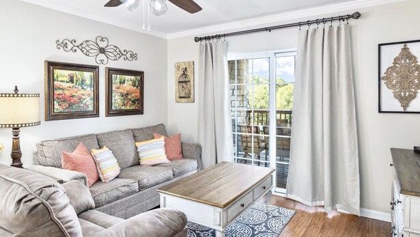 A living room with a grey sofa, a wooden coffee table, and a ceiling fan. - Next to Silver Dollar City, King Master, 2BR 2BA, Full Size Kitchen, 20ft Patio (Branson)