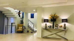 A modern interior with a staircase, a sofa, and a console table with decorative items. - Beautiful "Casa Grande" Luxury Villa in Davao City (Davao)