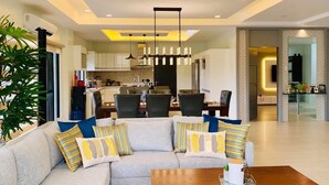 A modern living room with a sectional sofa, dining area, kitchen, and a hallway leading to another room. - Beautiful "Casa Grande" Luxury Villa in Davao City (Davao)