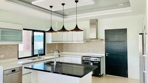 A modern kitchen with a central island, stainless steel appliances, and pendant lighting. - Beautiful "Casa Grande" Luxury Villa in Davao City (Davao)