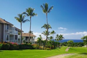 A beachfront property with a two-story building, palm trees, and a clear view of the ocean. - Wailea 2BR Villa Near Beach, Shops & Golf (Wailea)
