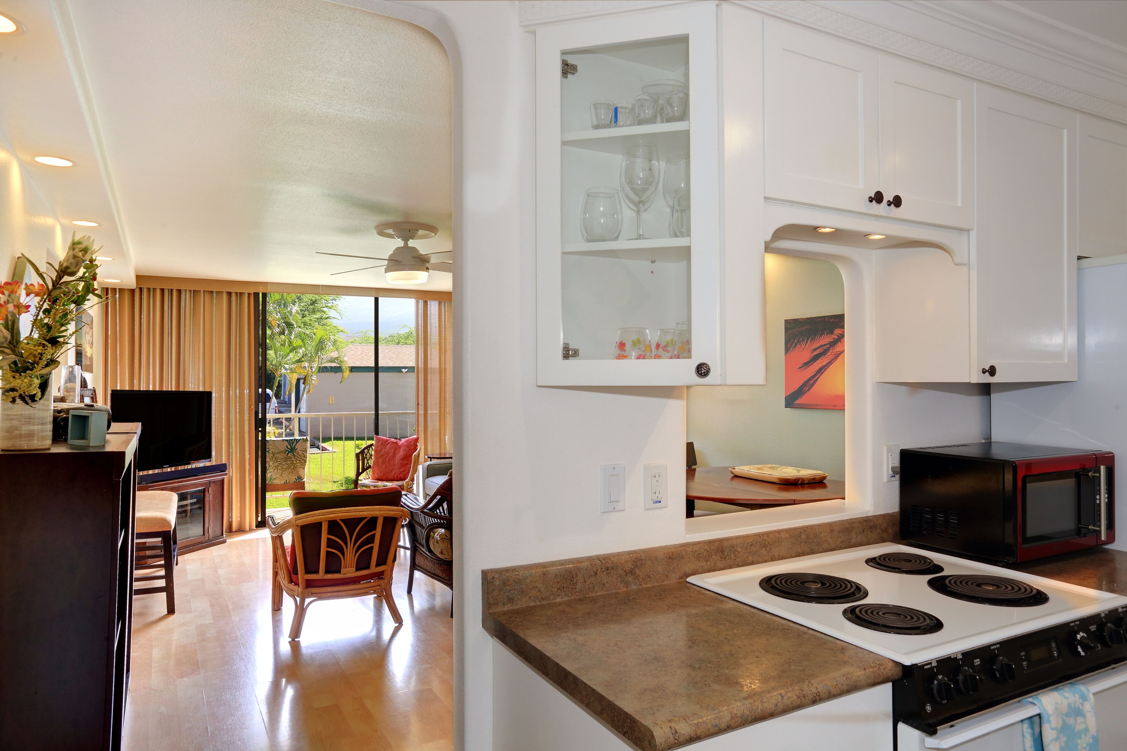 Cocina moderna con estufa, microondas y armarios. Hay un comedor con una silla y una mesa.