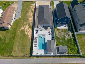 Vista aérea de um bairro residencial com piscina, várias casas e gramado bem cuidado.