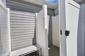 A narrow hallway with a white door and a bench.