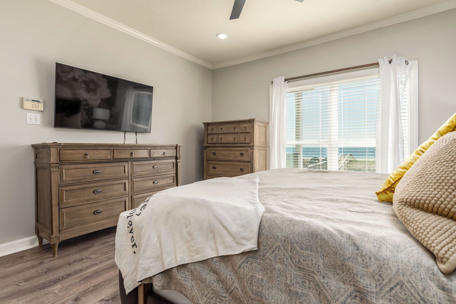 A bedroom with a bed, a dresser, a television, and a window with a view.