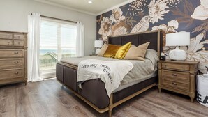 Une chambre à coucher comprenant un lit, des tables de chevet, une commode et une fenêtre avec des stores.