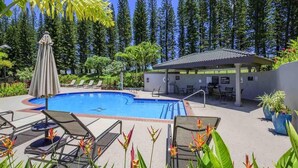 A pool area with lounge chairs, a covered seating area, and a building with a tiled roof. - Kapalua Golf Villa 20T5 Relax & Unwind (Kapalua)