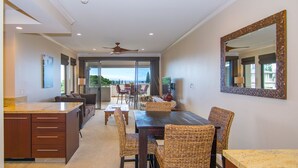 A spacious dining area with a large table and wicker chairs, a kitchen with a wooden countertop, and a ceiling fan. - Kapalua Golf Villa 20T5 Relax & Unwind (Kapalua)