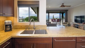 A modern kitchen with a double sink, a coffee maker, and a large window overlooking a scenic view. - Kapalua Golf Villa 20T5 Relax & Unwind (Kapalua)