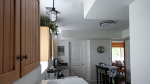 Une cuisine avec des meubles de rangement en bois, un plan de travail blanc et un coin repas comprenant une table et des chaises.