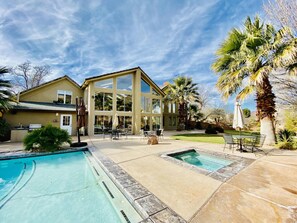 A modern house with a large glass facade, a swimming pool, and a patio area with outdoor furniture. - Luxury Home and Property with 2 Private Pools and Pickleball Court (Saint George)