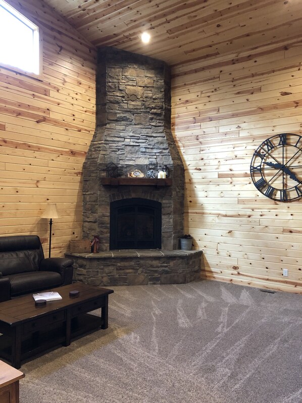 Cozy seating area with a fireplace, leather sofa, and dartboard.