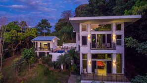 A modern two-story house with a balcony, a pool, and a dining area. - 4BR Luxury Villa • 4 King Suites • Ocean & Sunset Views • Private Pool (Manuel Antonio)