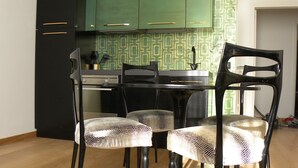 Un coin repas comprenant une table ronde, quatre chaises et un luminaire suspendu.