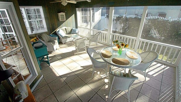 A covered patio with a round table, chairs, and a ceiling fan. - Patti's 1625 Bungalow | East Beach St. Simons Island Cottage with Pool (Saint Simons Island)