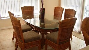 A dining area with a glass-top table surrounded by wicker chairs with cushioned seats. - Luxury Villa on main Rotonda canal (Rotonda West)