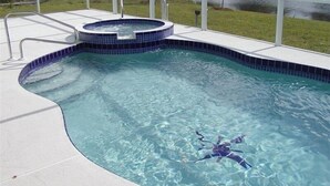 A swimming pool with a hot tub, surrounded by a glass enclosure, and a view of a river. - Luxury Villa on main Rotonda canal (Rotonda West)