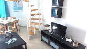 A modern living room with a black entertainment unit, a TV, and a spiral staircase.