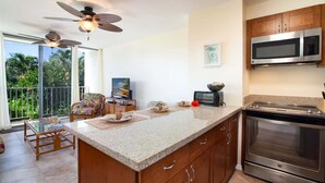 Una cocina con una isla grande, microondas, horno y ventilador de techo.