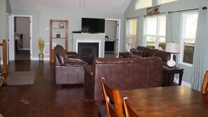 A spacious living room with a fireplace, leather sofas, a dining table, and a ceiling fan. - Super Location in Lakeside Estates--w/pool; basketball ct; walking tr; boat ramp (Lafollette)