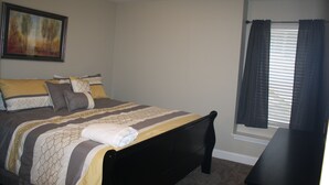 A bedroom with a bed, a nightstand, a window with curtains, and a painting on the wall. - Super Location in Lakeside Estates--w/pool; basketball ct; walking tr; boat ramp (Lafollette)