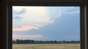 A window view of a field with a clear sky and some clouds. - Relax At The Farm!   Newly Built Studio Apartment In The Barn At Selah Farm (Kalispell)