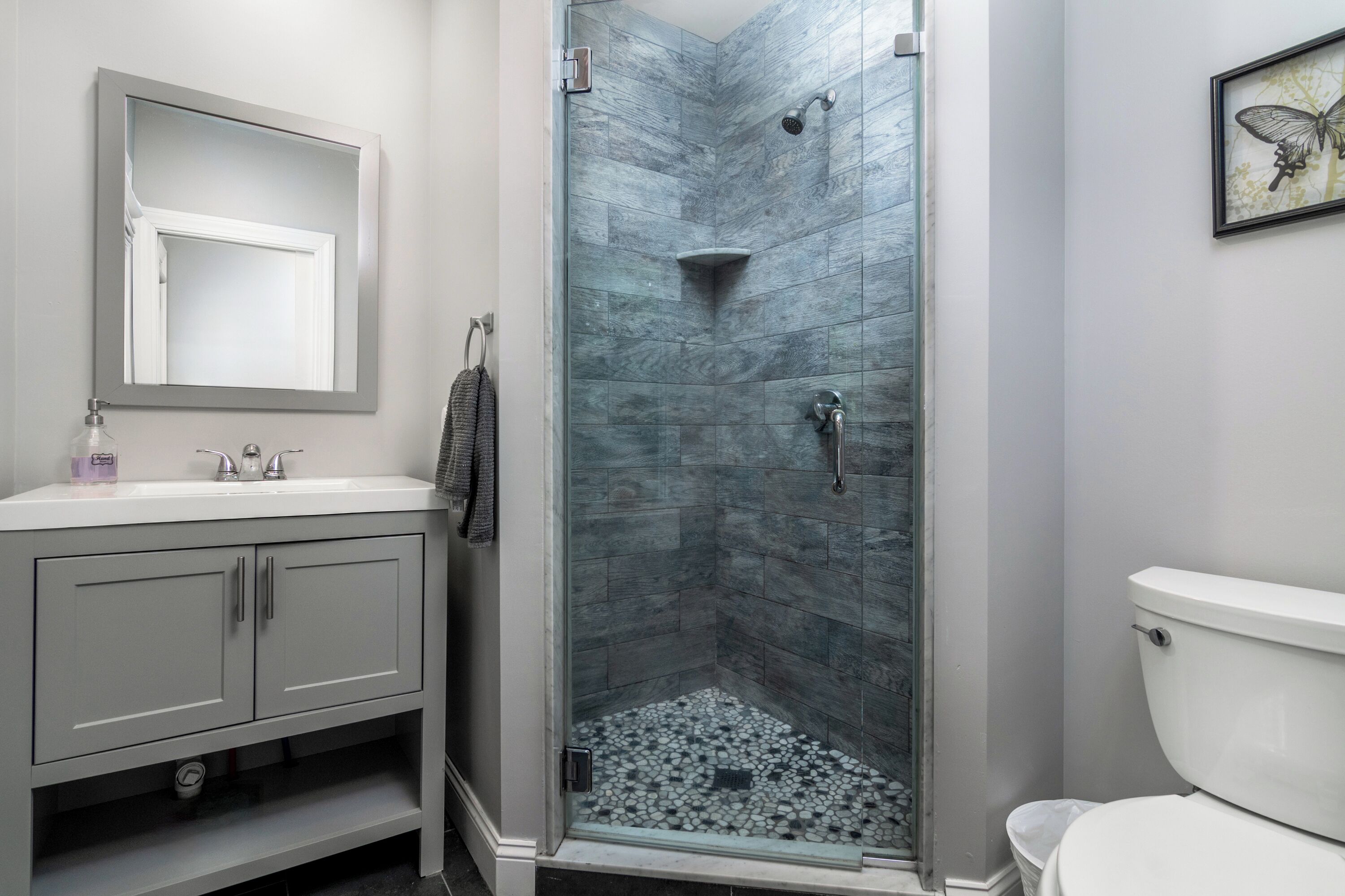 Un baño con cabina de ducha de vidrio, lavamanos blanco y retrete.