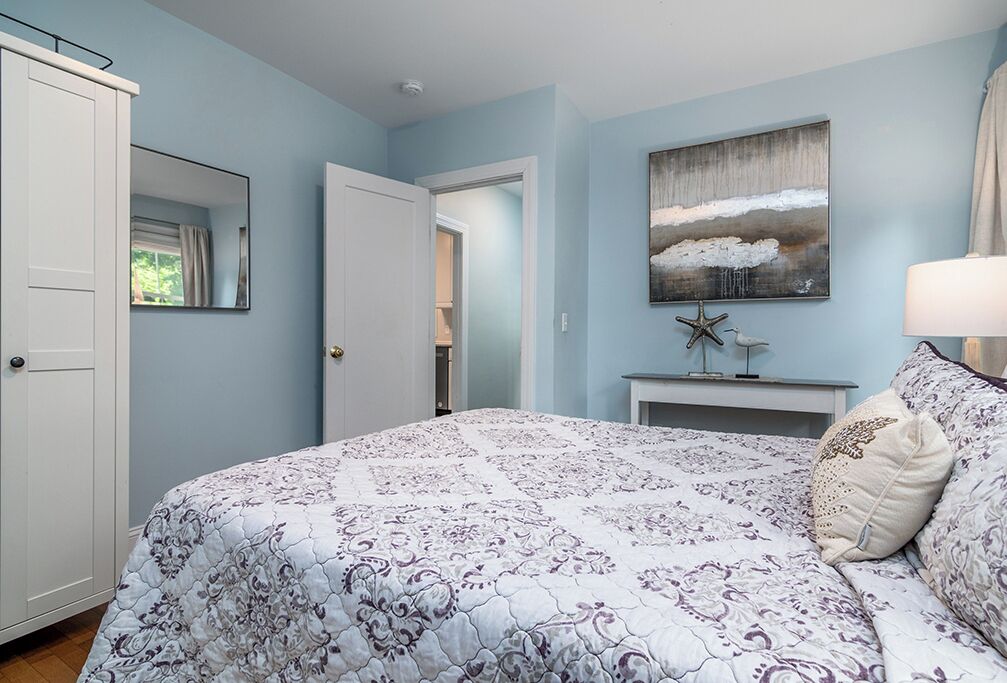 A bedroom with a large bed, a dresser, a nightstand, and a painting on the wall.
