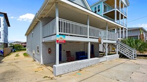 A two-story building with a balcony, a sign for 'Saltwater Rentals,' and a staircase leading to the upper level. - "Sand Dollar Suites" suite 1: A short stroll from our sandy shores! (Carolina Beach)