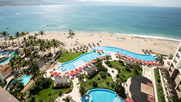 Um resort com ampla área de piscina, acesso à praia e vista para o oceano.