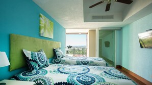 Quarto com duas camas, um ventilador de teto e uma varanda com vista.